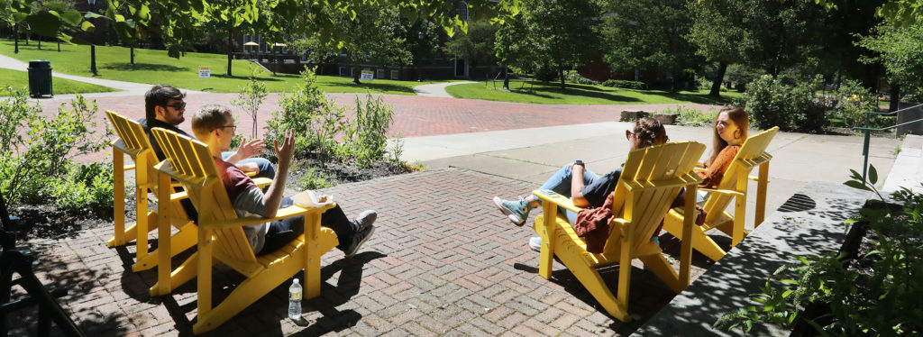 Alumni sitting in adirondack chairs outside of Carr Hall. Photo by Ed Mailliard.