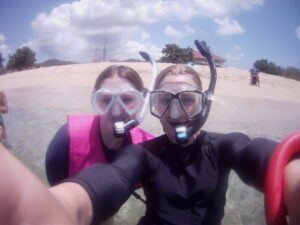 Two students wearing snorkel masks on a beach