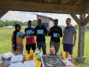 YBL Youth pictured at a senior give-away with Lugundi, outdoors at a community garden.
