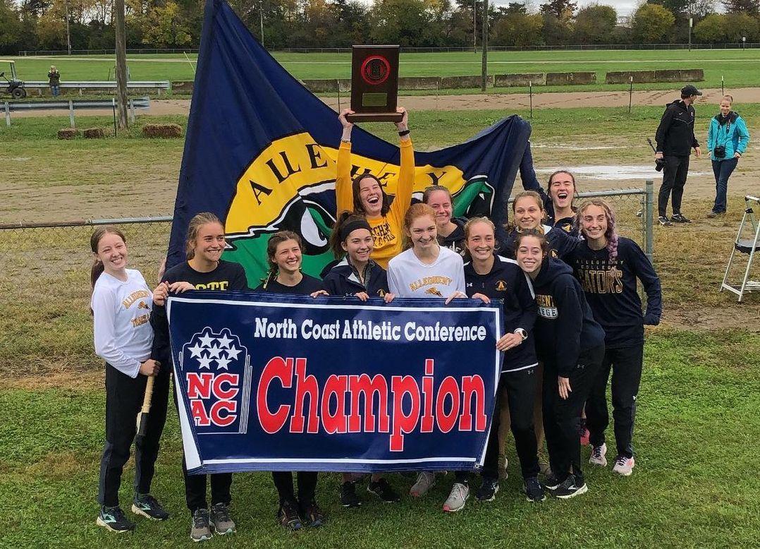 The Gator Women's Cross Country team with an NCAC champion banner