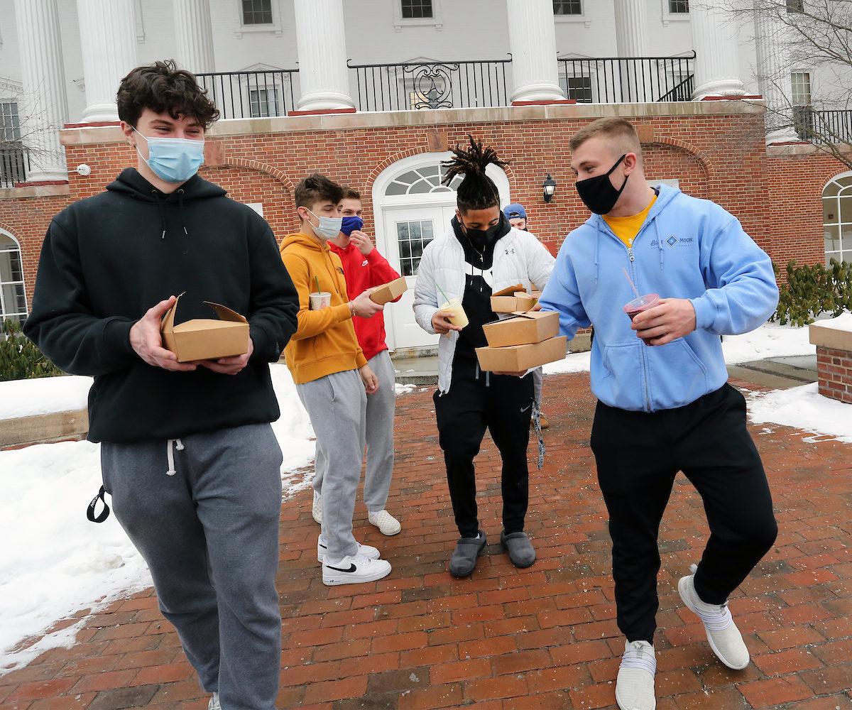 students holding takeout food containers outside of Brooks Hall