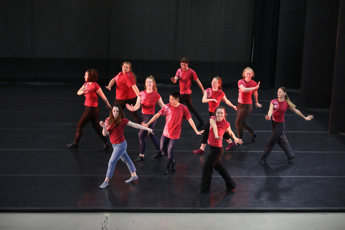 students in red shirts dance on stage