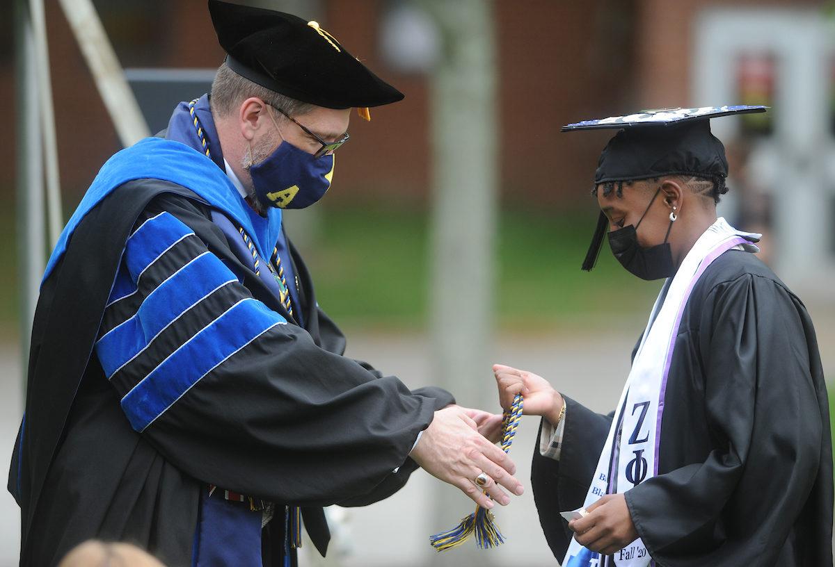 A student receives graduation cords from a faculty member