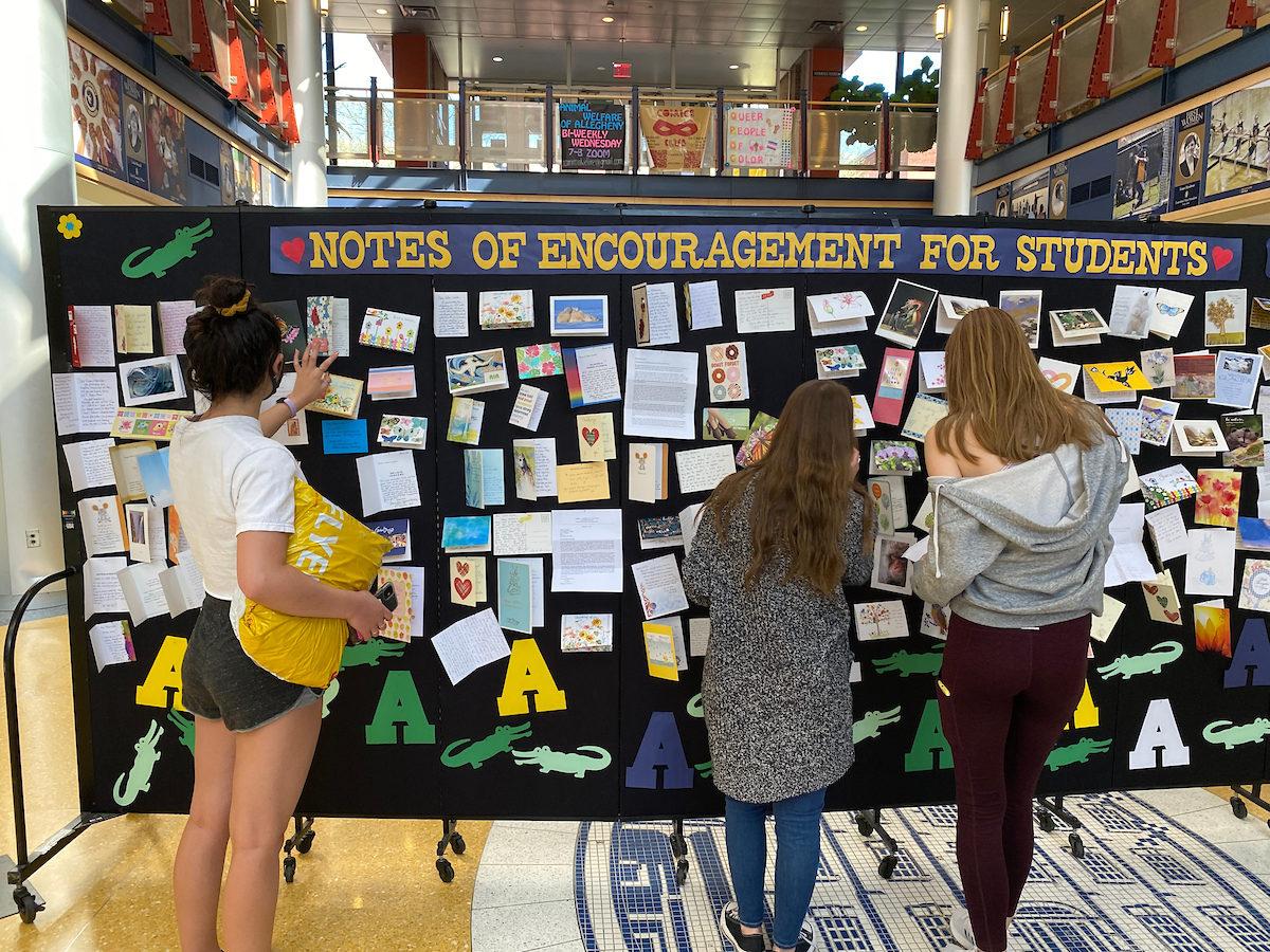 students look at a bulletin board with handwritten cards