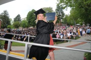 Student displays a diploma holder as she exists the commencement stage