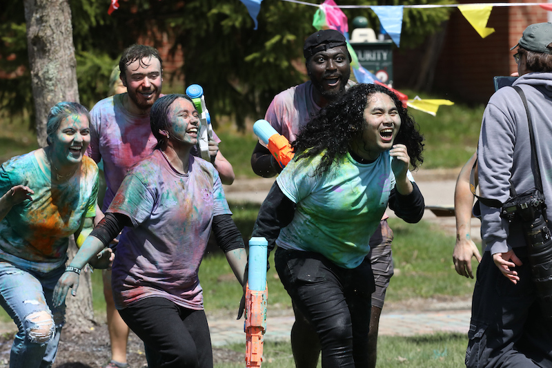 Students smiling while covered in colorful powder