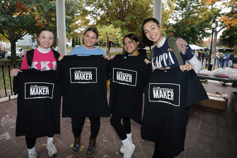 four students hold T-shirts reading "difference maker"