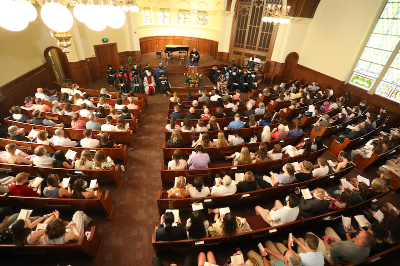 aerial view of people seated in chapel with officials presenting from the stage