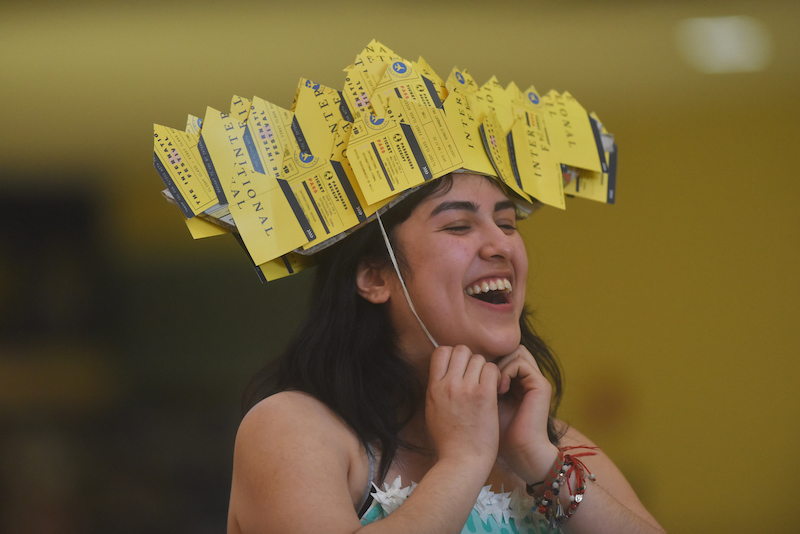 student smiles while wearing a hat made from discarded paper