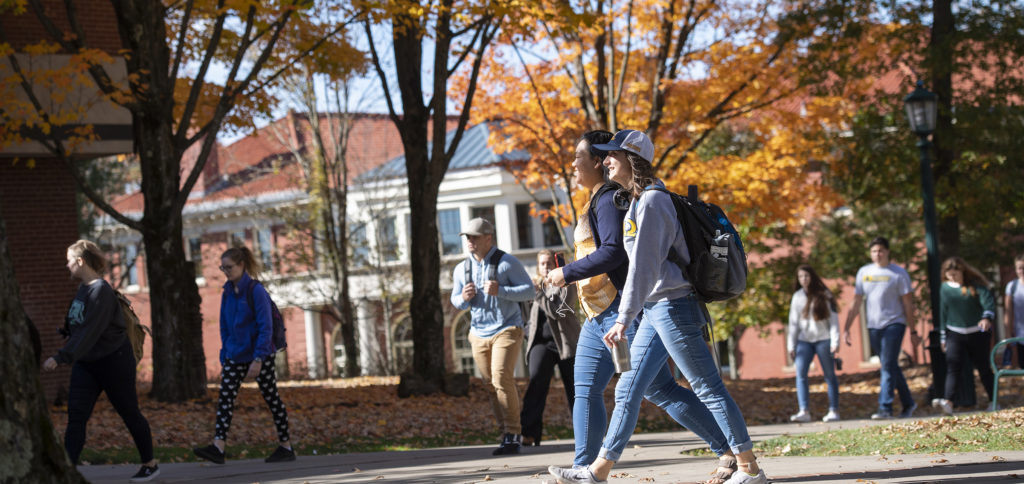 Students walk across campus carrying backpacks in the fall time.